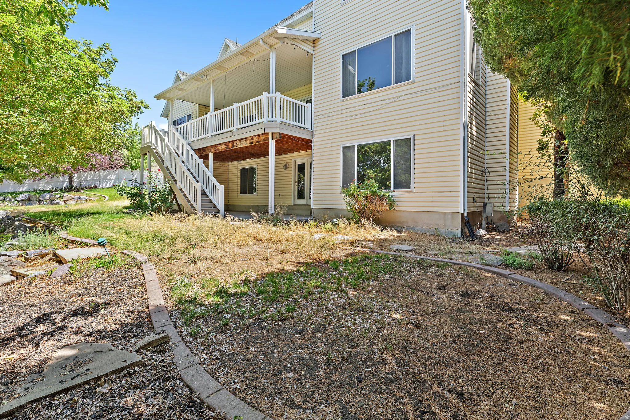 Rear exterior with siding, featuring a covered upper-level deck with white railings and an outdoor staircase