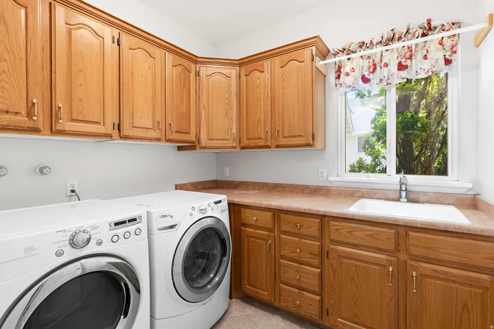 Functional laundry area featuring extensive wood cabinetry, a utility sink, and ample counter space