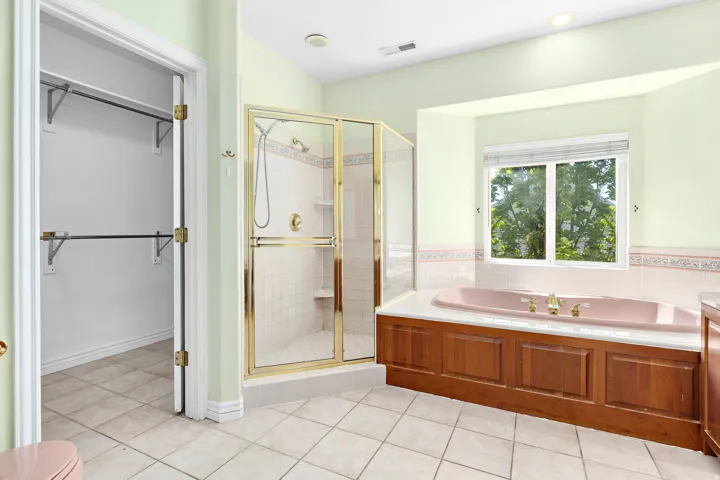 Bathroom featuring a built-in soaking tub with a wood-paneled surround, a glass-enclosed shower, and ceramic tile flooring