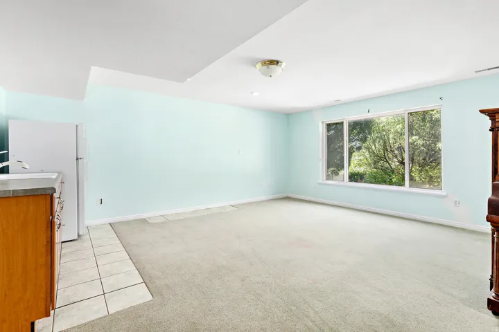 Spacious room featuring a large window, light blue painted walls, and a recessed ceiling section