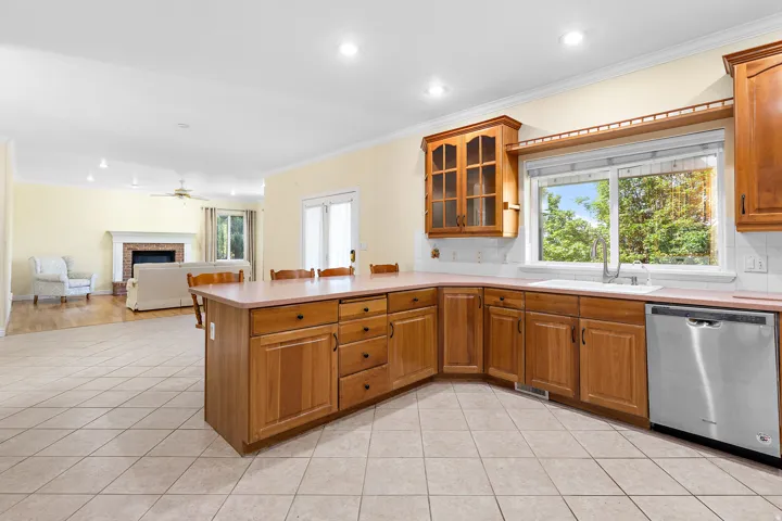 Kitchen featuring wood cabinetry, stainless steel dishwasher, and a large window above the sink