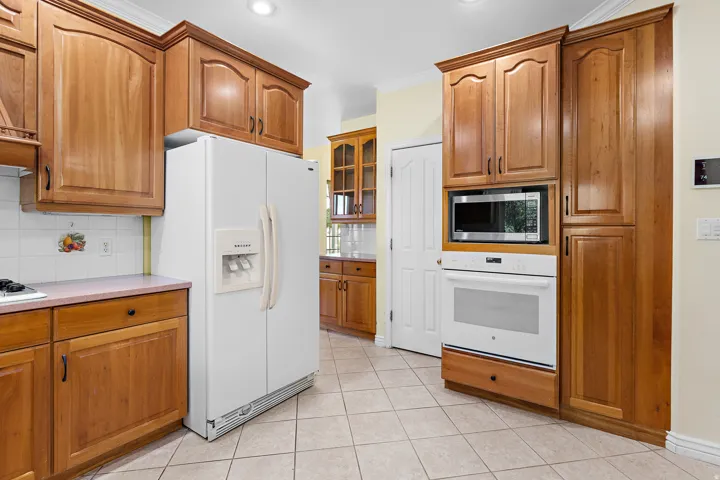 Kitchen featuring wood cabinetry, built-in microwave, wall oven, and tile flooring