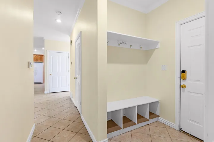 Entryway featuring a built-in bench with cubby storage, an overhead shelf with coat hooks, and durable tile flooring