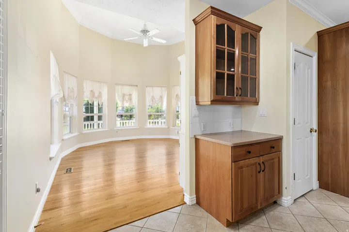 Bright living space featuring a bay window wall with multiple windows, wood-finish flooring, and a ceiling fan