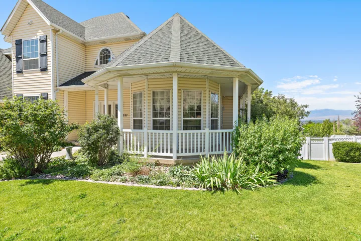 Exterior featuring light-colored siding, a covered polygonal porch with white railing, and multiple gabled rooflines