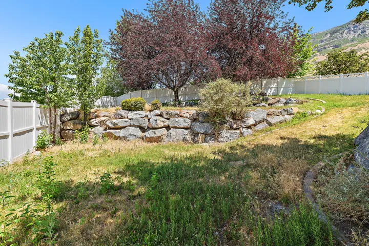 Tiered landscaping featuring a natural rock retaining wall and established trees