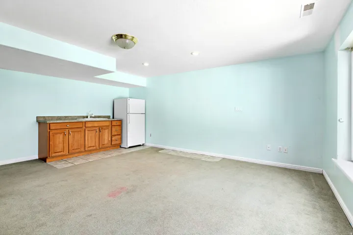 Spacious room featuring a built-in wood-finish cabinetry with an integrated sink and stone-look countertop