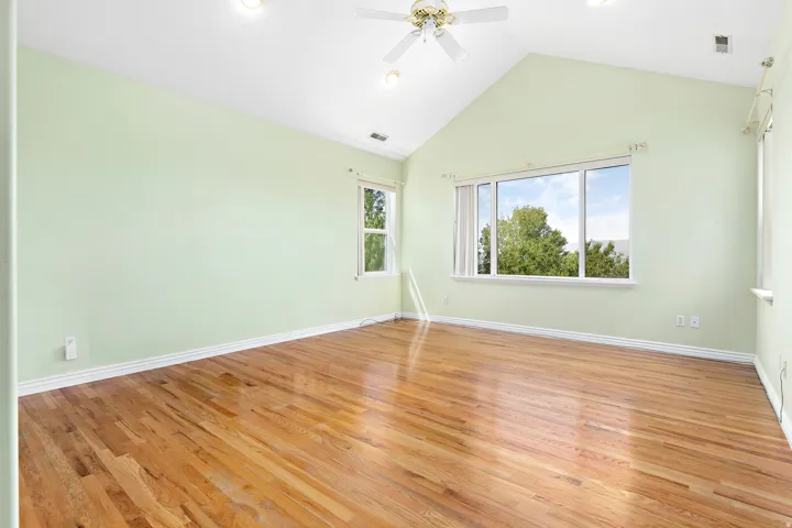 Vaulted ceiling room featuring wood-finish flooring, recessed lighting, a ceiling fan, and multiple windows