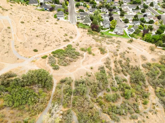 Natural landscape featuring varied topography, scattered shrubbery, and established residential areas