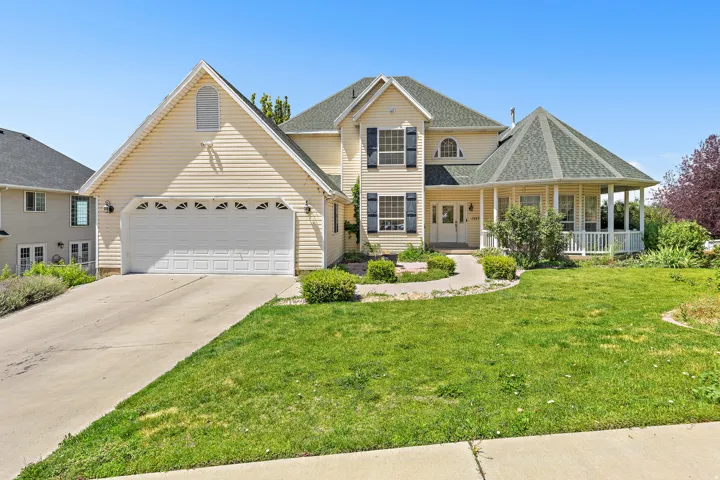 Light yellow siding exterior with a multi-gabled roofline and a prominent two-car garage