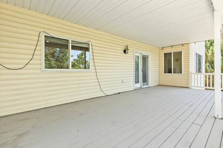 Expansive covered deck featuring a light gray wood-finish floor, white ceiling, and white siding