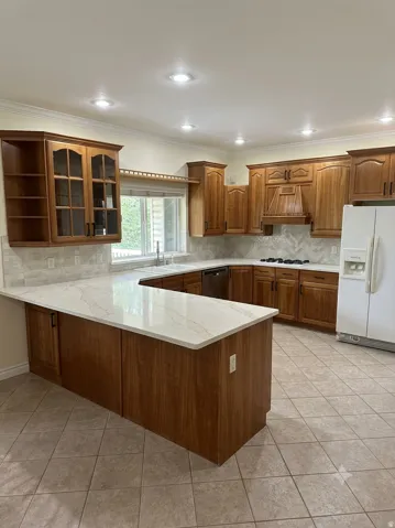AI generated image by Make It Market Ready. U-shaped kitchen featuring wood cabinetry, white countertops, tile flooring, and recessed lighting