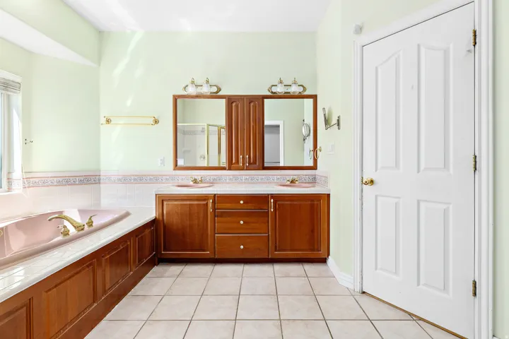 Dual vanity with wood cabinetry, two integrated sinks, and individual mirrors