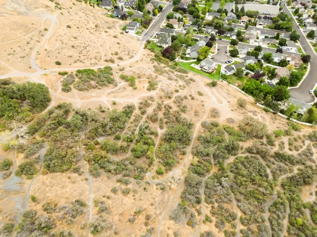 Expansive terrain featuring natural vegetation, visible pathways, and proximity to residential development
