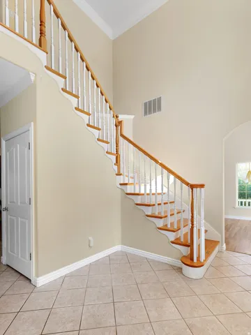 Two-story entry featuring a staircase with wood treads, painted white risers, and wood newel posts