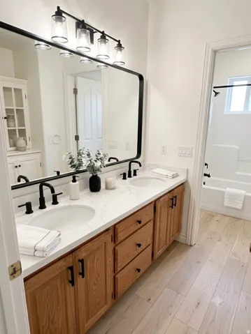 AI generated by Make It Market Ready. Double vanity with under-mount sinks, wood-finish cabinetry, and a light-toned countertop