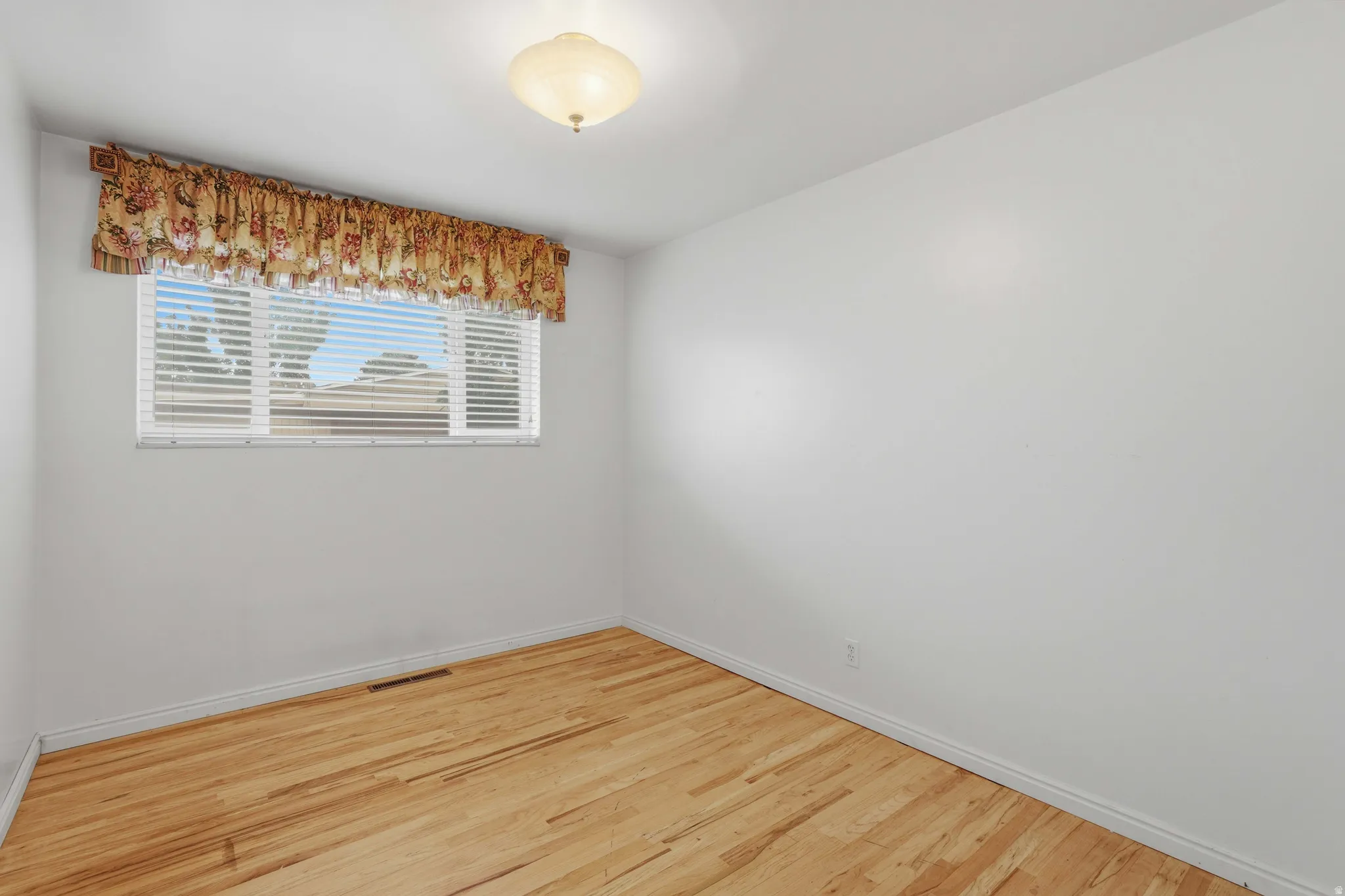 Bright interior space featuring light wood-finish flooring and white baseboards