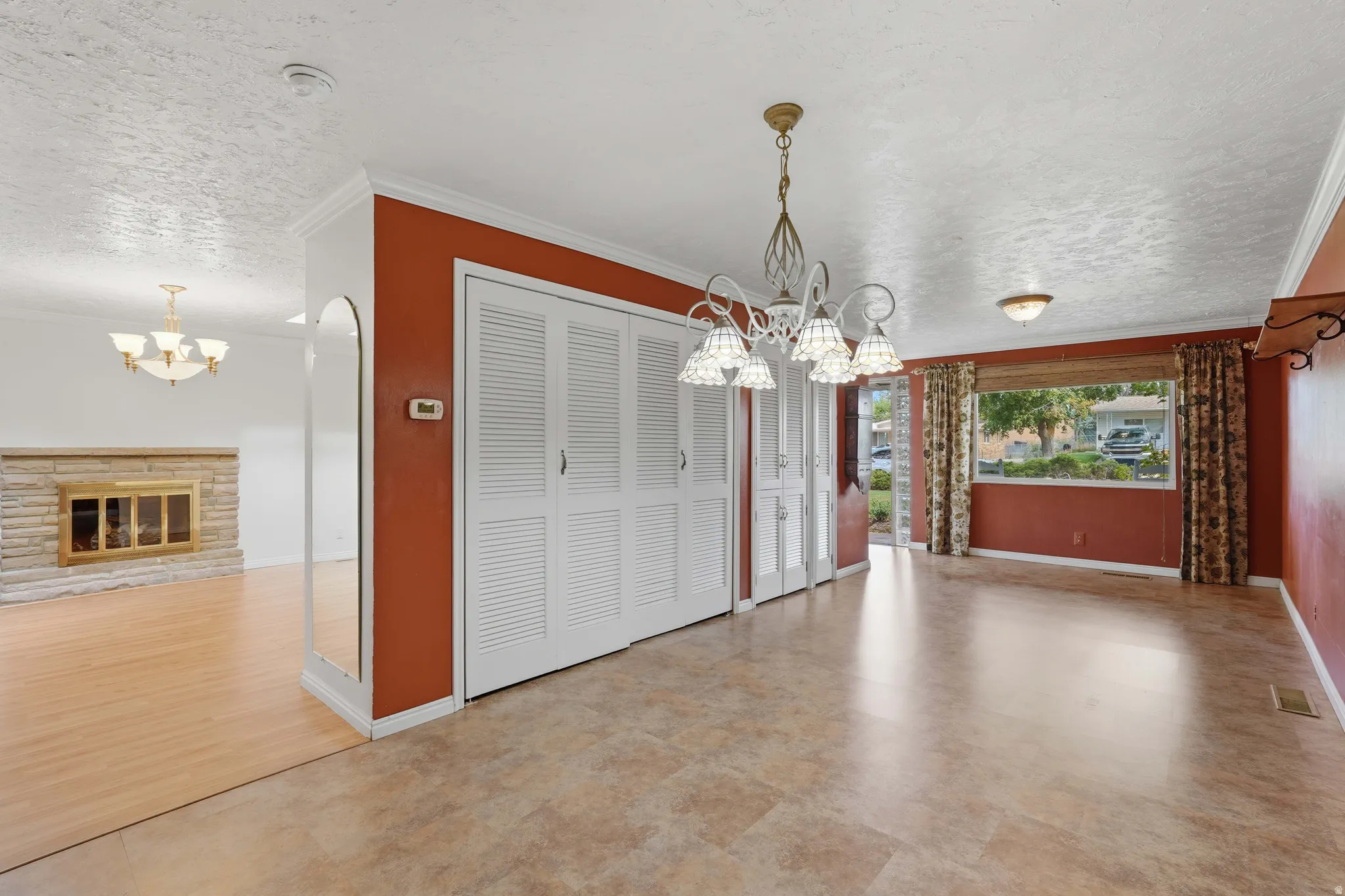 Spacious room featuring durable tile-look flooring, louvered bi-fold doors, and a decorative chandelier