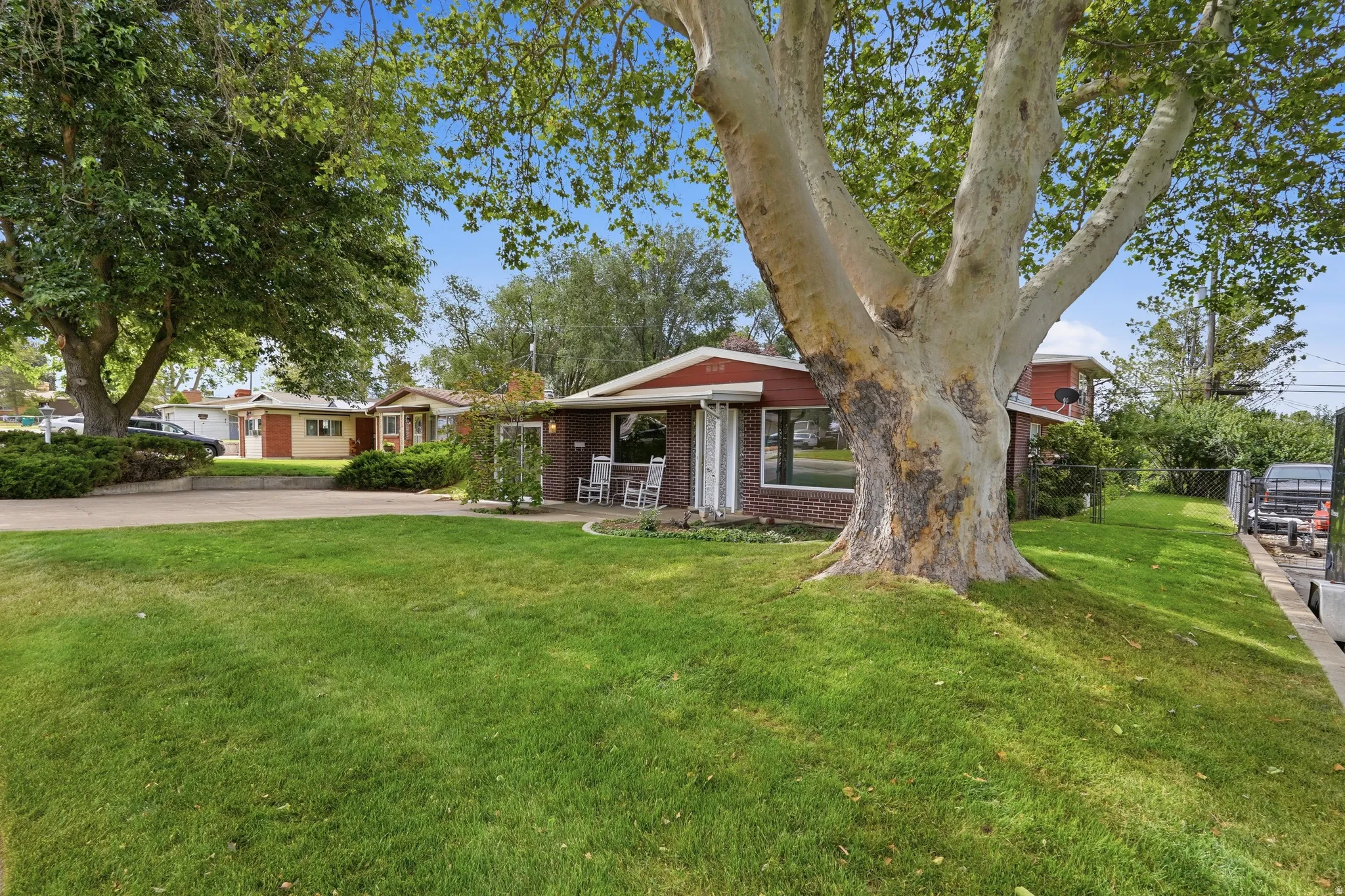 Expansive green lawn with mature shade trees providing natural coverage