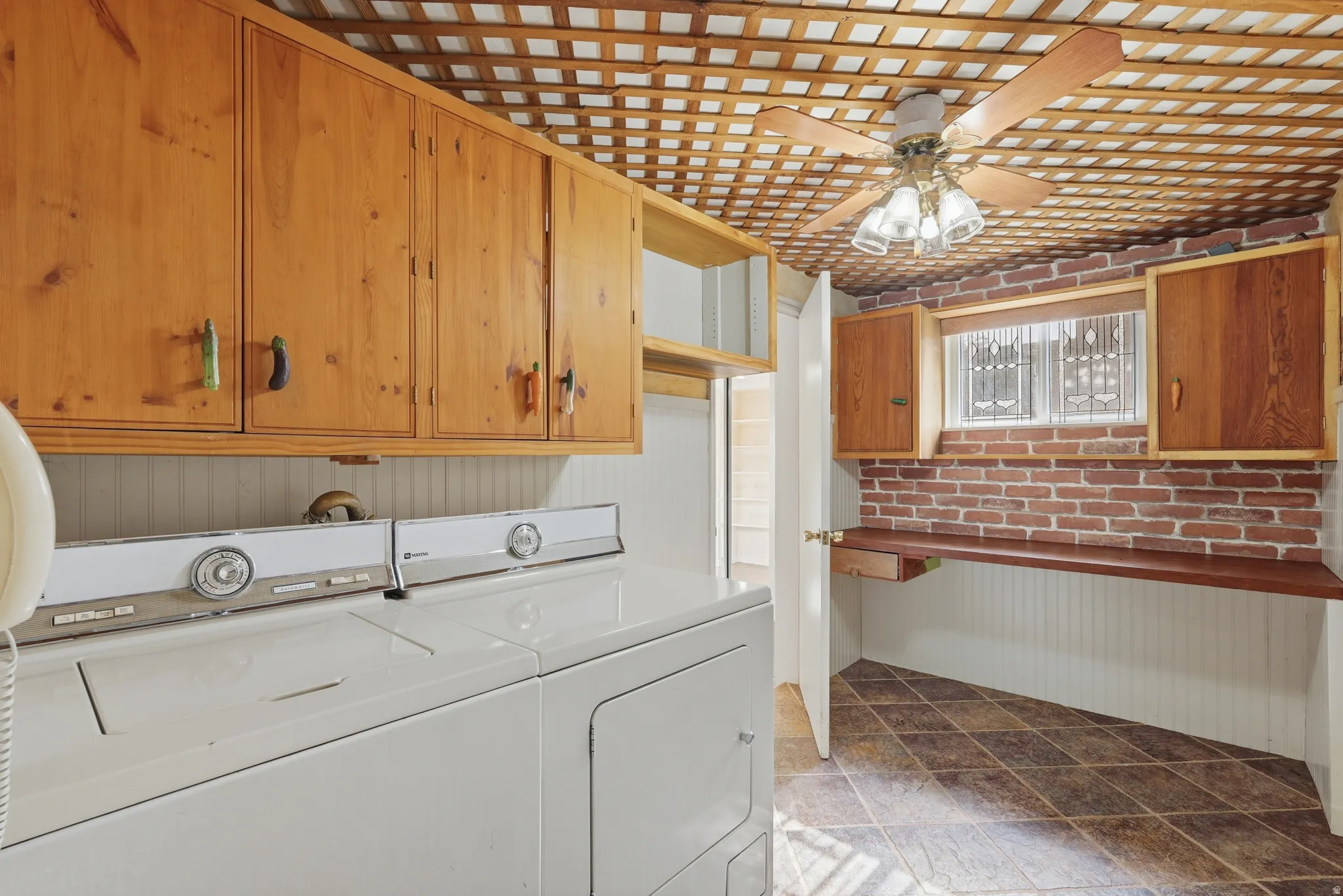 Dedicated utility space featuring extensive wood cabinetry, a built-in wood countertop, and a decorative brick accent wall