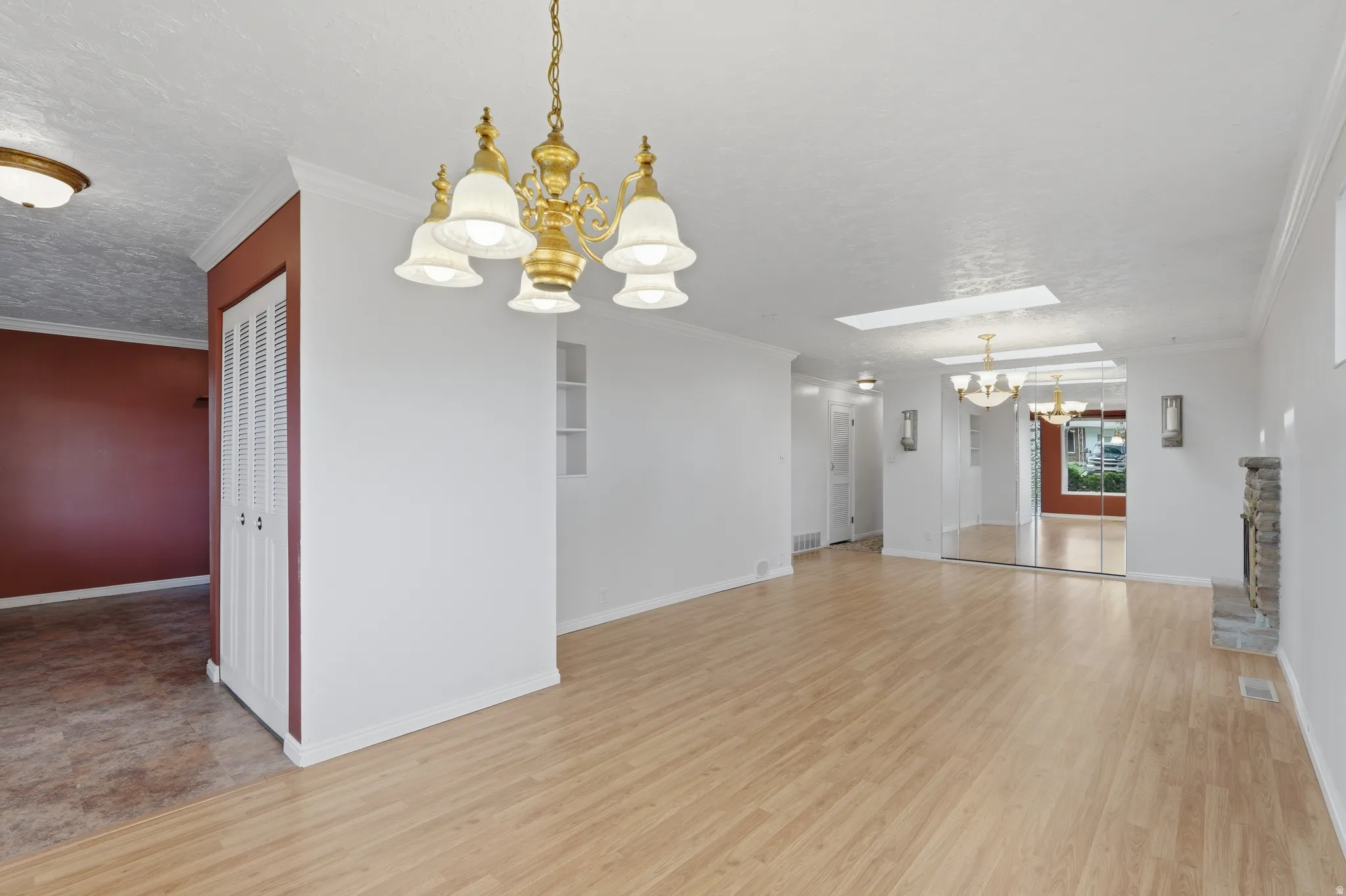 Spacious interior with wood-finish flooring, a brass chandelier, and a stone fireplace