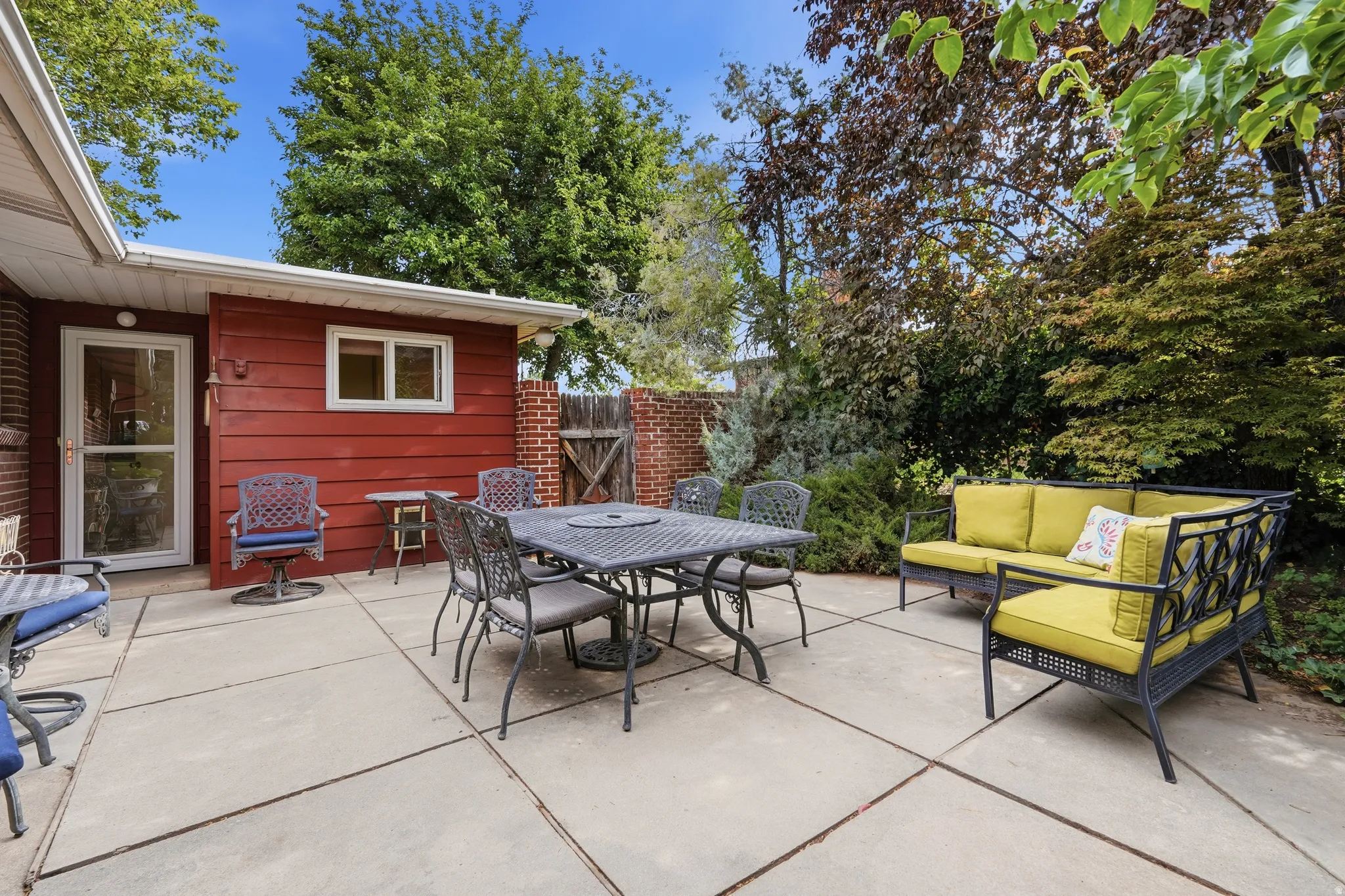 Expansive concrete patio area, featuring a red horizontal siding exterior wall with a white-framed window and a glass-paneled door