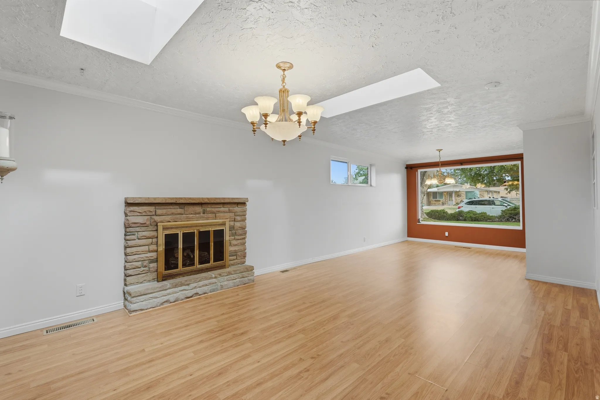 Spacious interior featuring wood-finish flooring, a stone-faced fireplace, and a large front-facing picture window