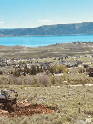 Expansive property featuring an excavator performing groundwork on a sloped terrain with natural vegetation