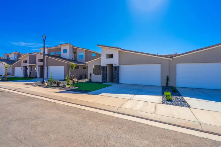 View of front of property with concrete driveway, stucco siding, an attached garage, and stone siding