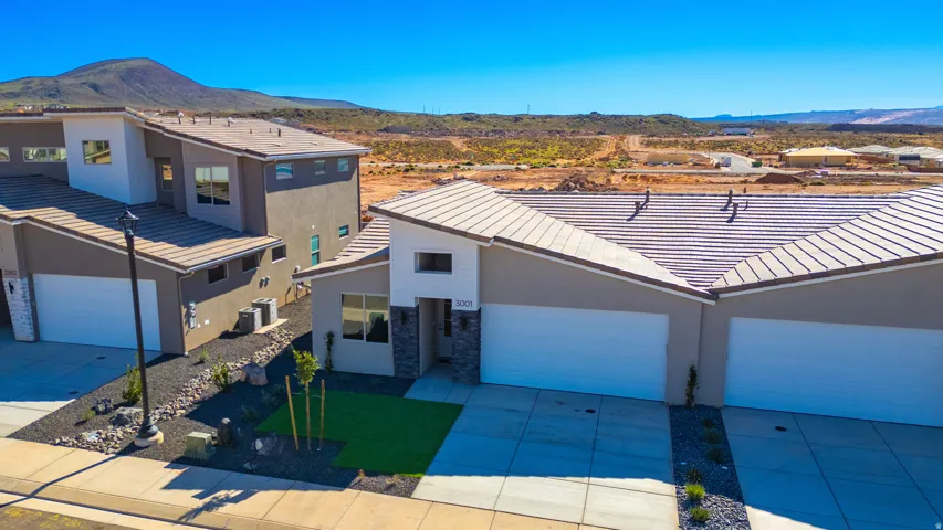 View of front facade with a mountain view, stucco siding, concrete driveway, a tile roof, and stone siding