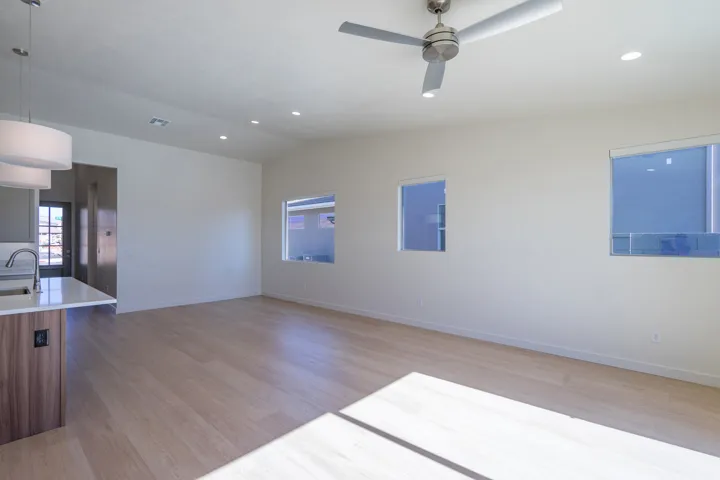 Spare room featuring light wood-type flooring, lofted ceiling, recessed lighting, a ceiling fan, and plenty of natural light