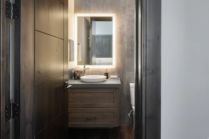 Modern vanity featuring a vessel sink, integrated LED mirror, and built-in storage