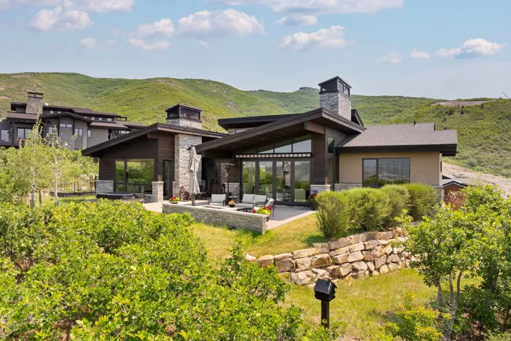 Contemporary exterior with stone and wood-finish siding, featuring a spacious patio area
