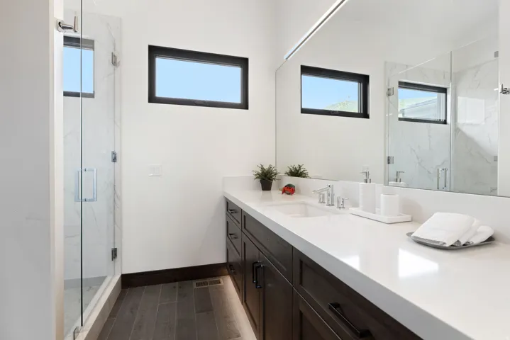 Contemporary bathroom featuring a dark wood-finish vanity with a white countertop and integrated sink