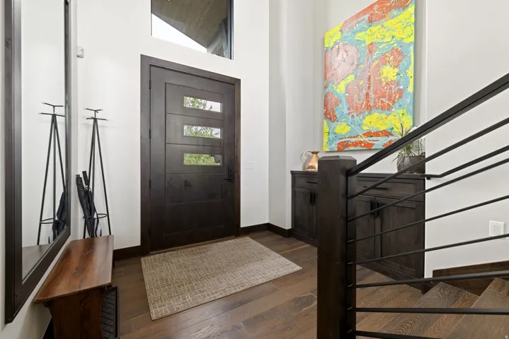 Modern entryway featuring a dark wood-finish door with three horizontal lites, a transom window, and rich wood-finish flooring