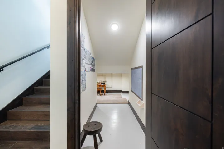 Hallway with white flooring, contemporary dark wood-finish door, and recessed ceiling lighting