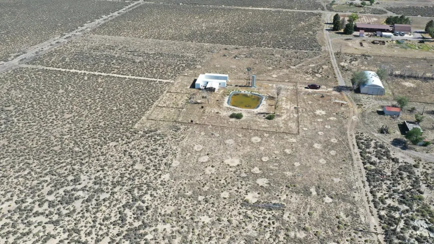 Expansive land parcel featuring a main building, detached metal barn, a pond, and a windmill