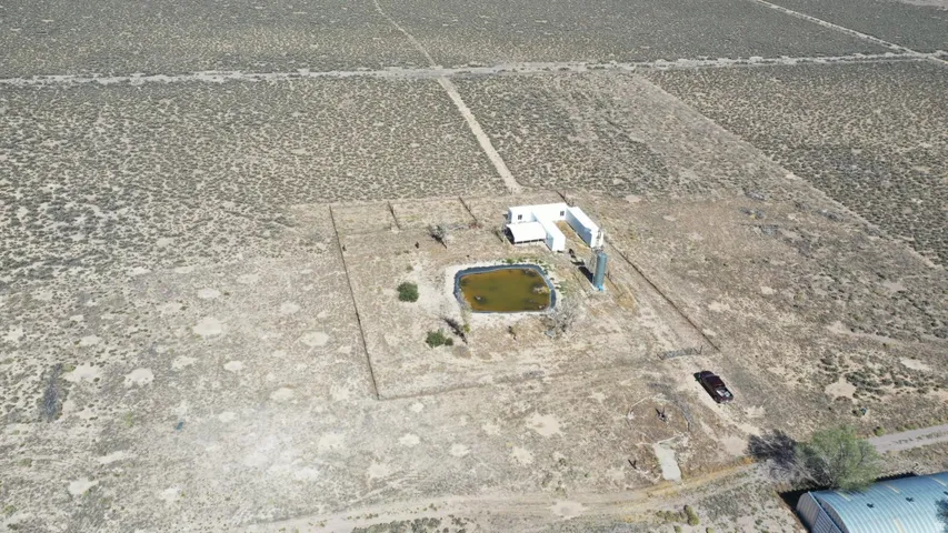 Expansive desert property featuring a fenced compound with multiple structures