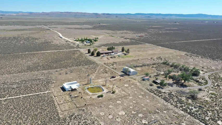 Expansive desert landscape featuring multiple structures, a winding driveway, and large tracts of open land