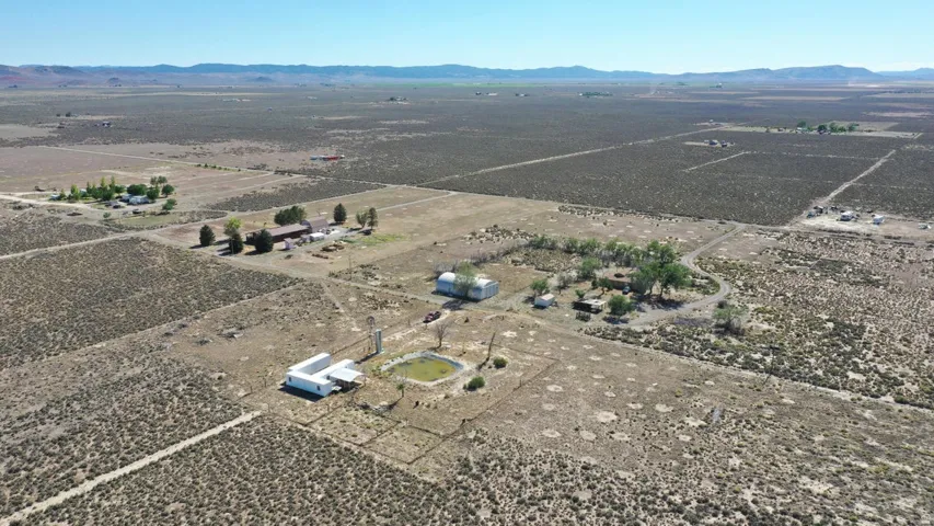 Expansive high desert property featuring multiple structures, a visible pond, and extensive undeveloped land