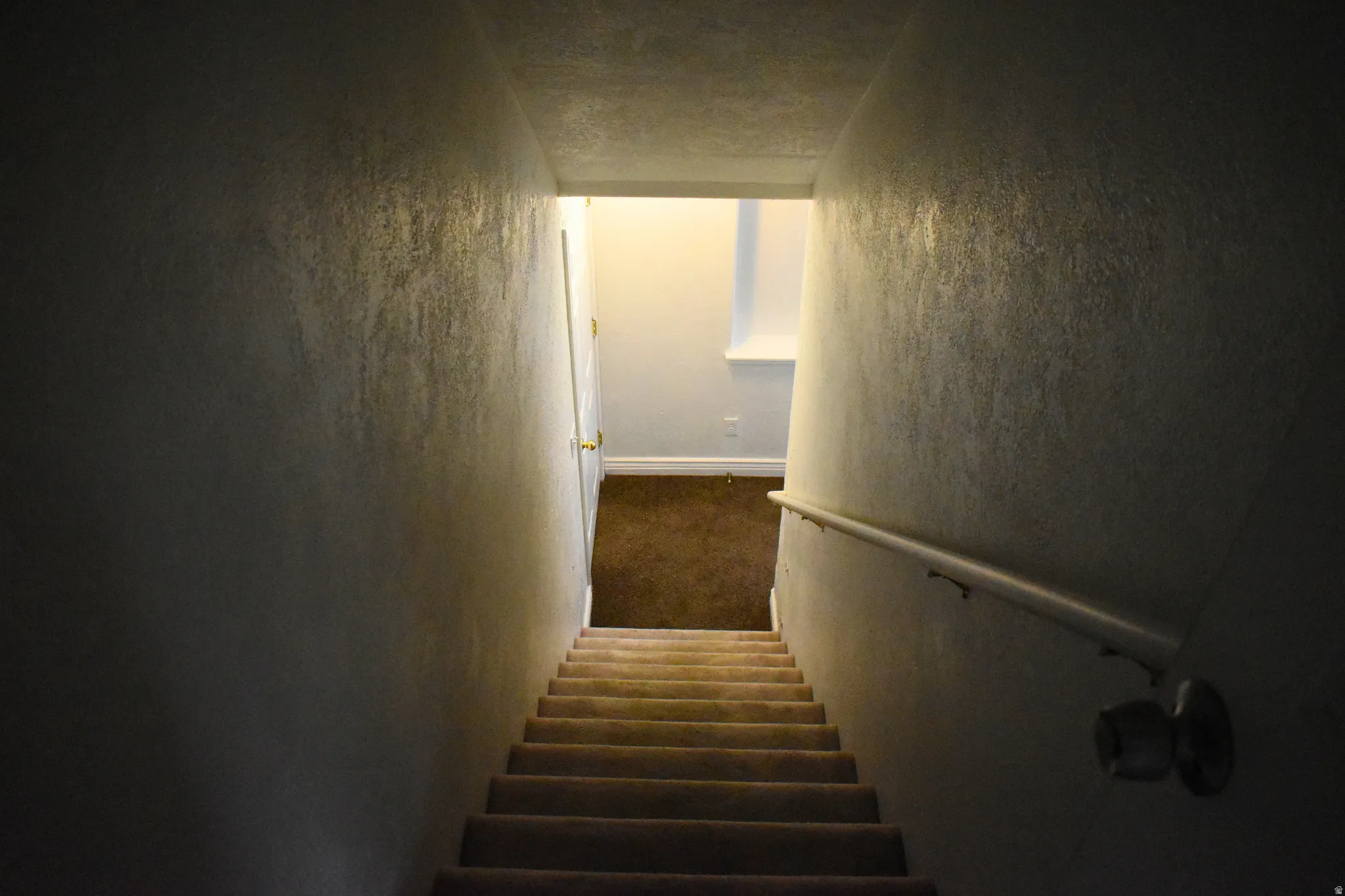 Carpeted staircase with a white handrail