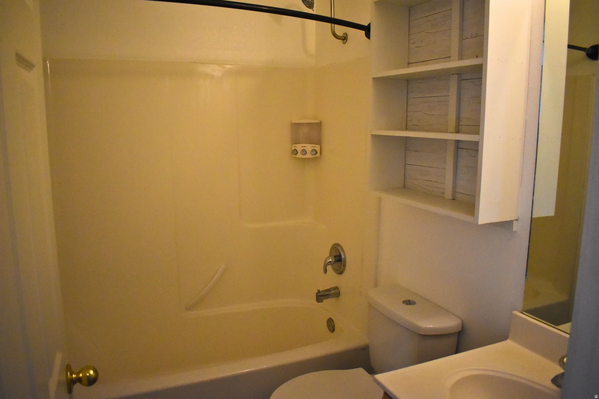 Bathroom featuring a white bathtub with a shower combination, toilet, and vanity with an integrated sink