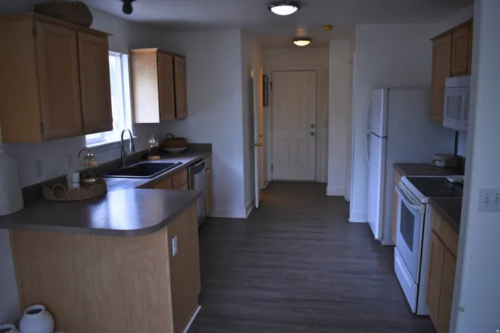 Kitchen featuring wood-finish cabinetry, dark countertops, and wood-finish flooring
