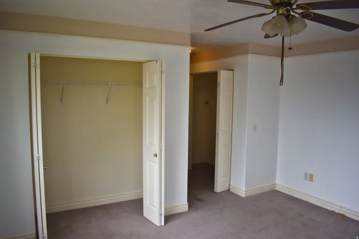 Bedroom featuring carpeting, white walls, and a ceiling fan with light fixture