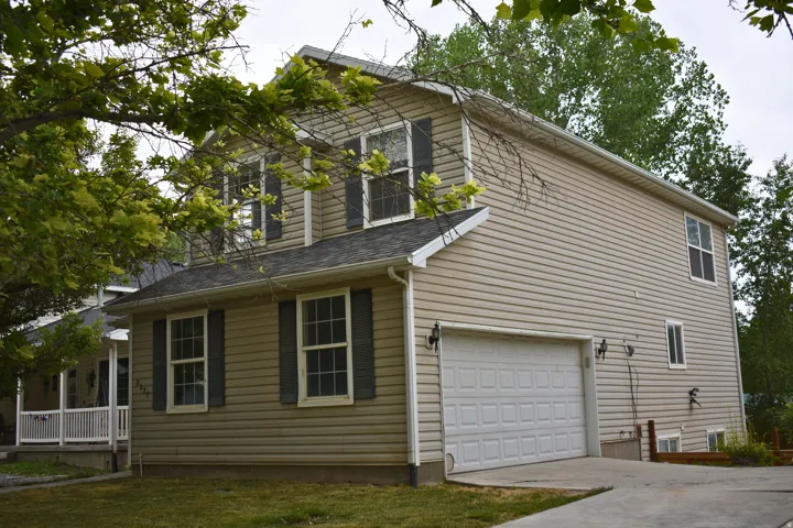 Two-story residence featuring light-colored siding, a dark shingle roof, and an attached two-car garage with a panel door