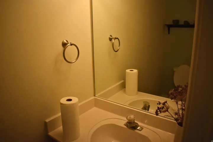 Half bath main level. Vanity area featuring a white integrated sink, chrome faucet, and a large wall-mounted mirror