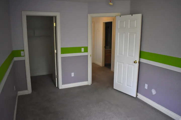 Carpeted room with a closet, white trim, and a six-panel interior door