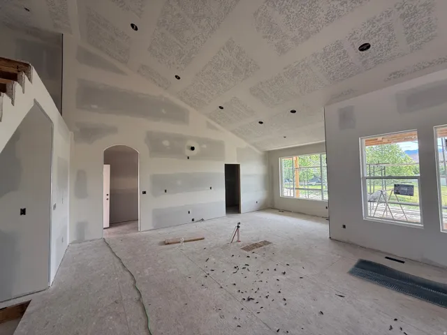 Expansive living area under construction featuring vaulted ceilings and recessed lighting