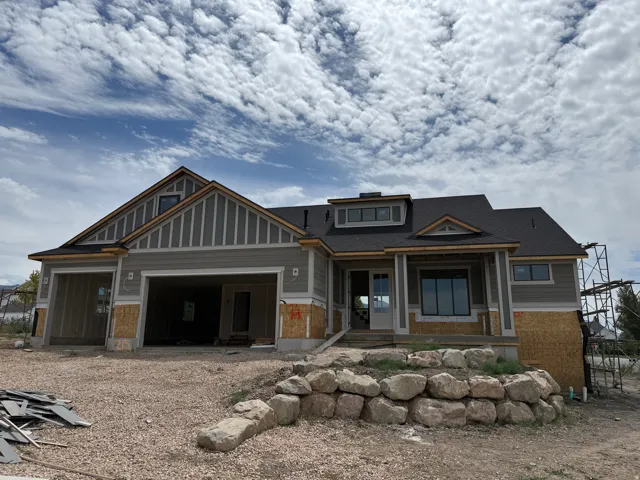Contemporary exterior featuring gray horizontal siding, dark gray roofing, a front porch, and a stone retaining wall