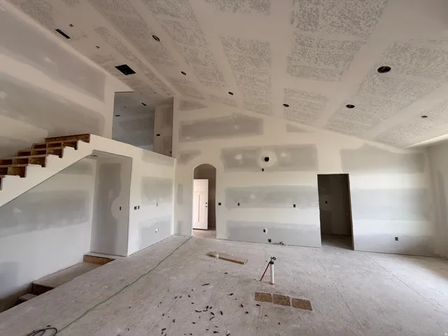 Spacious interior with vaulted ceilings, recessed lighting, an exposed wood staircase, an arched entryway, and multiple doorway openings